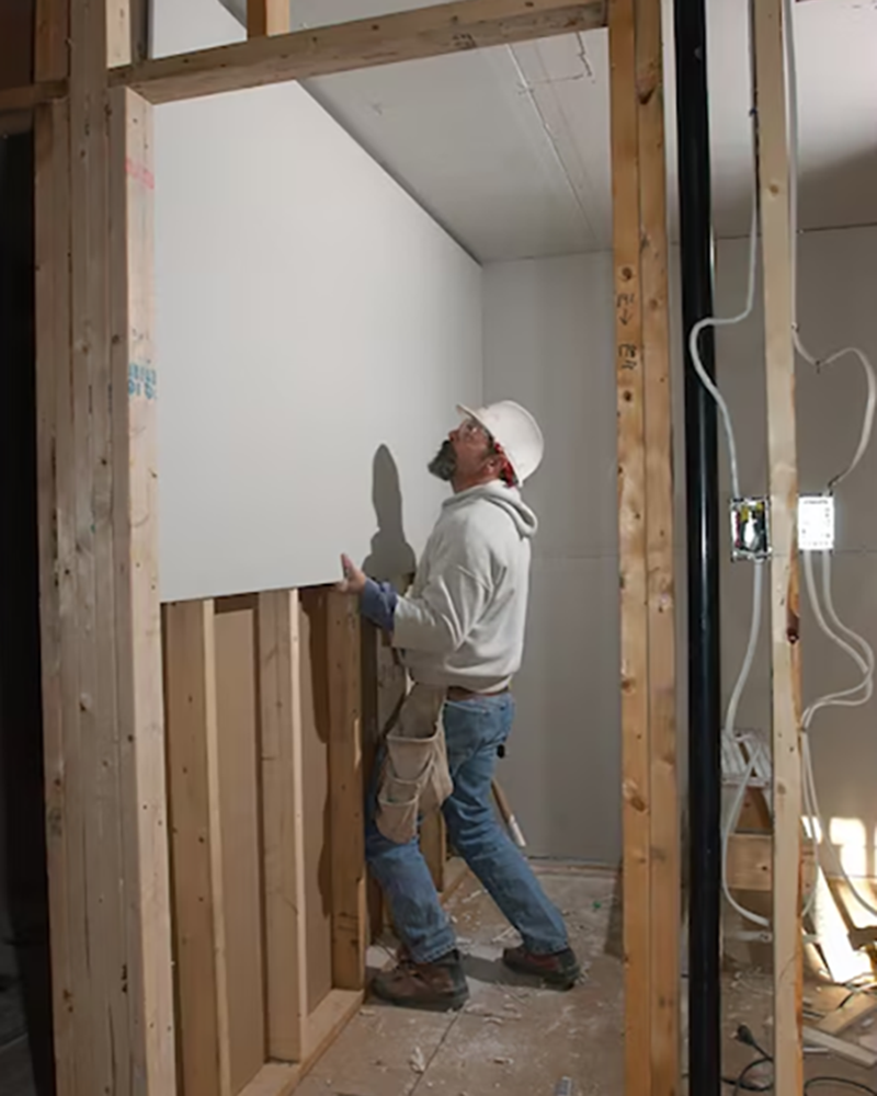 A contractor installing Type X fire-resistant drywall in a home.