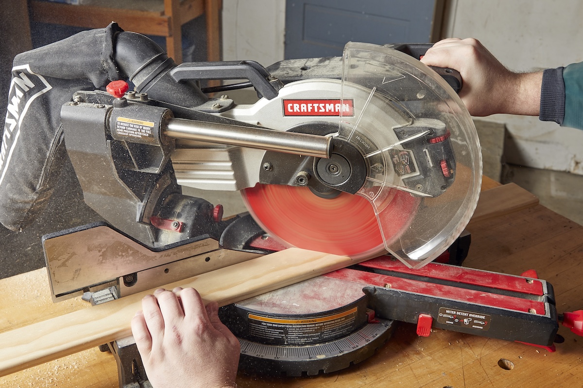 A DIYer using a miter saw to cut miter joints for window and door trim.