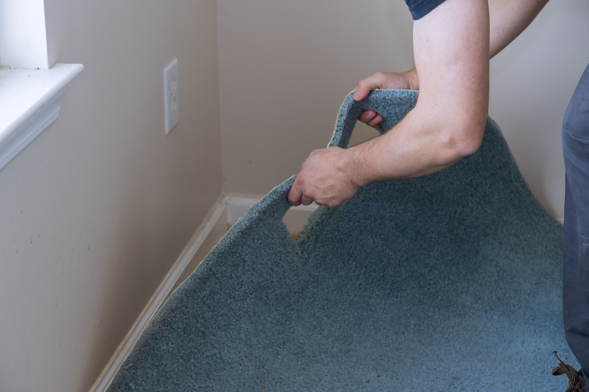 A homeowner removing old carpet getting ready to install new flooring.