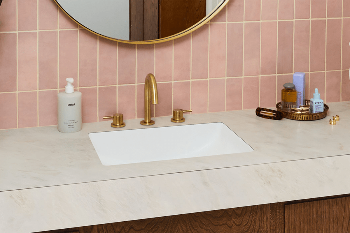 A white laminate countertop with sink and faucet in a home bathroom.