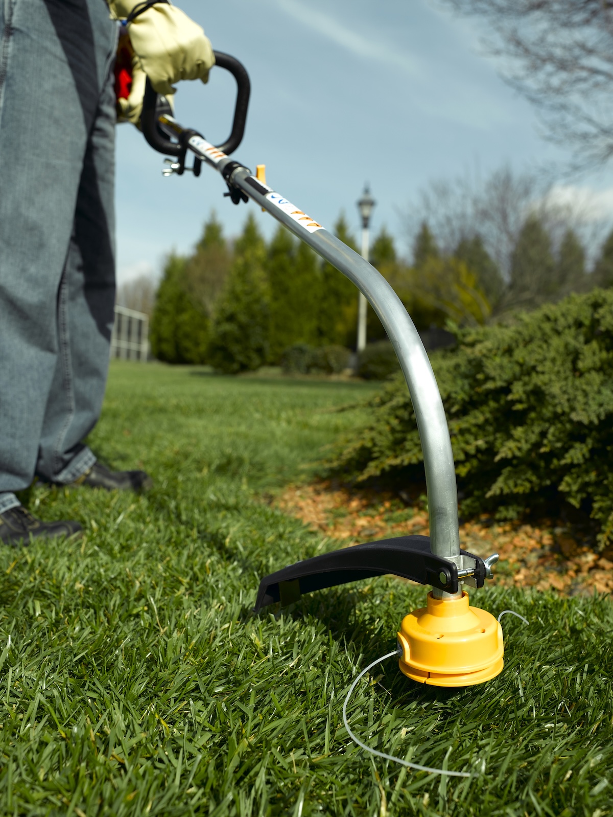 A person using a string trimmer on the lawn.