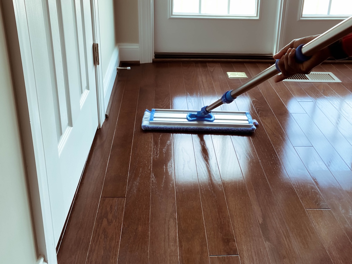 A homeowner cleaning vinyl plank flooring with a mop.