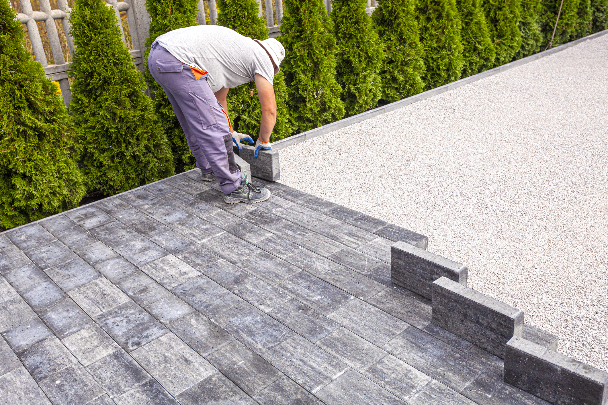 Man laying paving stones on a driveway. 