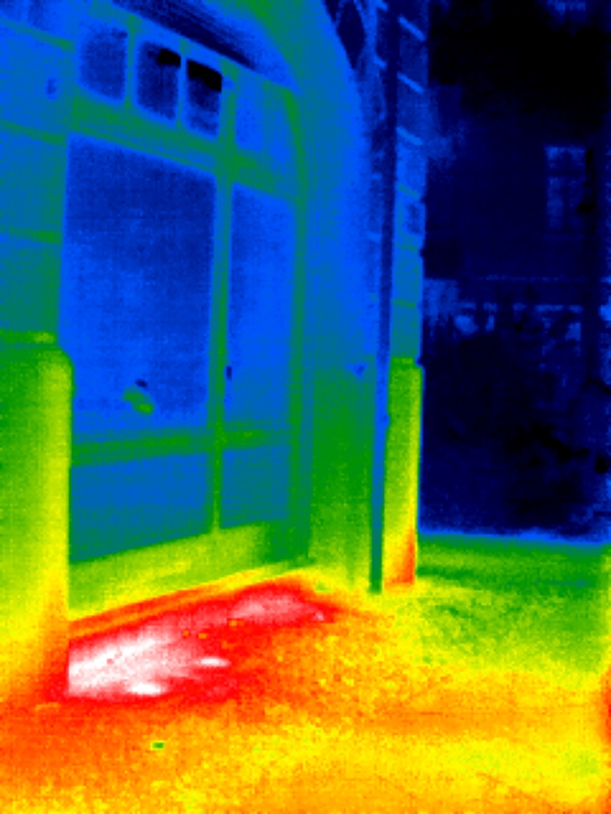 A thermal image of a house with heat loss coming from under a large window.