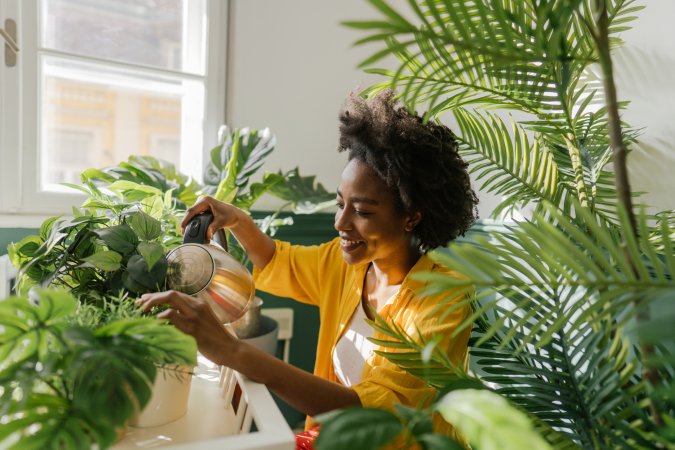 Young woman taking care of several houseplants