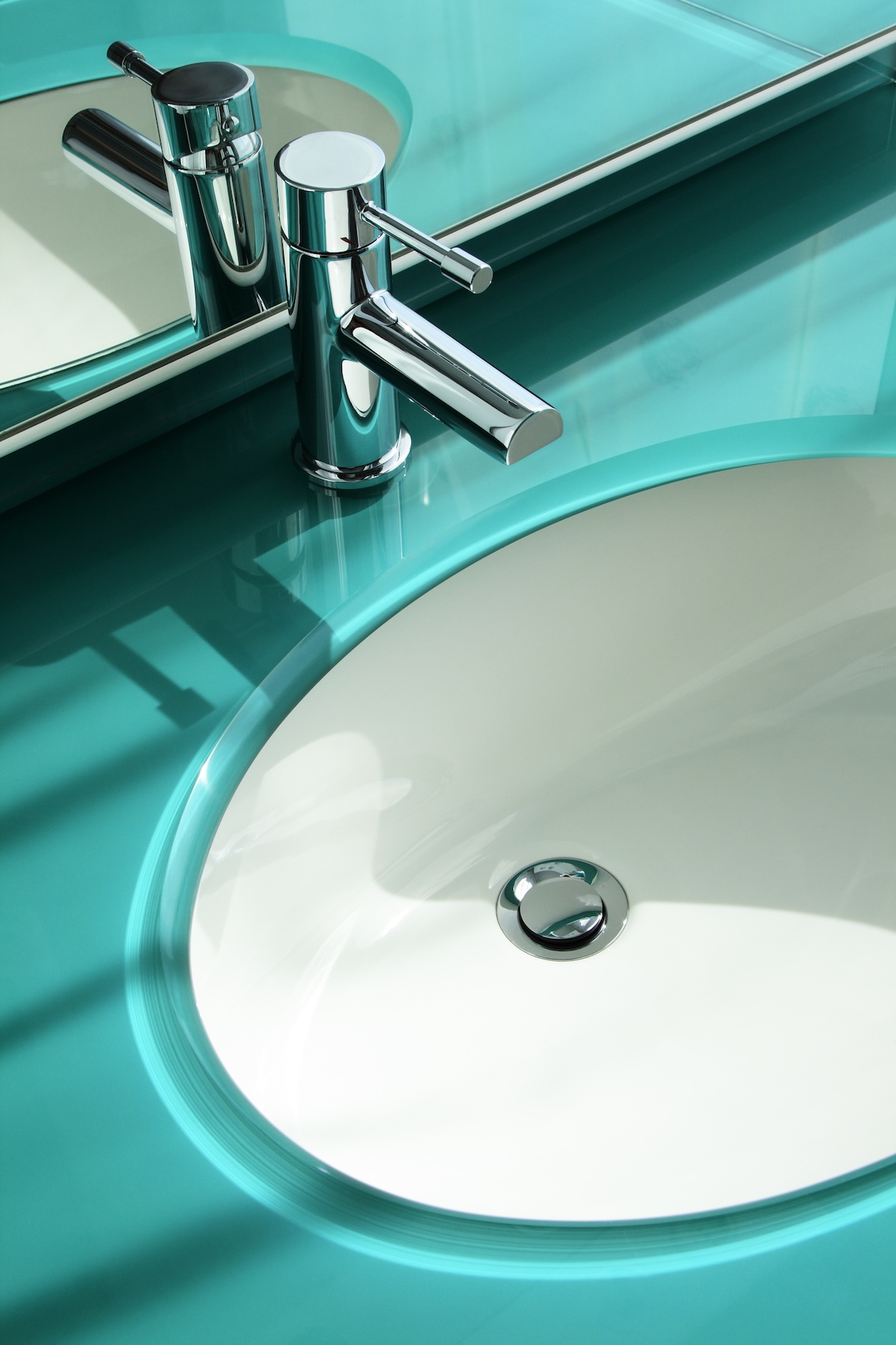 A glass bathroom vanity top with a sink in a home bathroom.