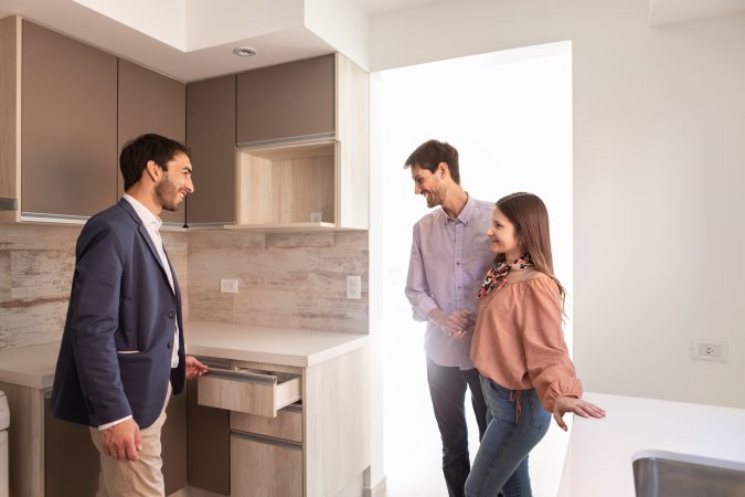 Young couple happy in their new kitchen as realtor gives them a tour of it.