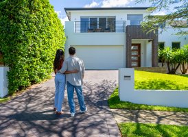 Happy Couple standing in front of their new home.