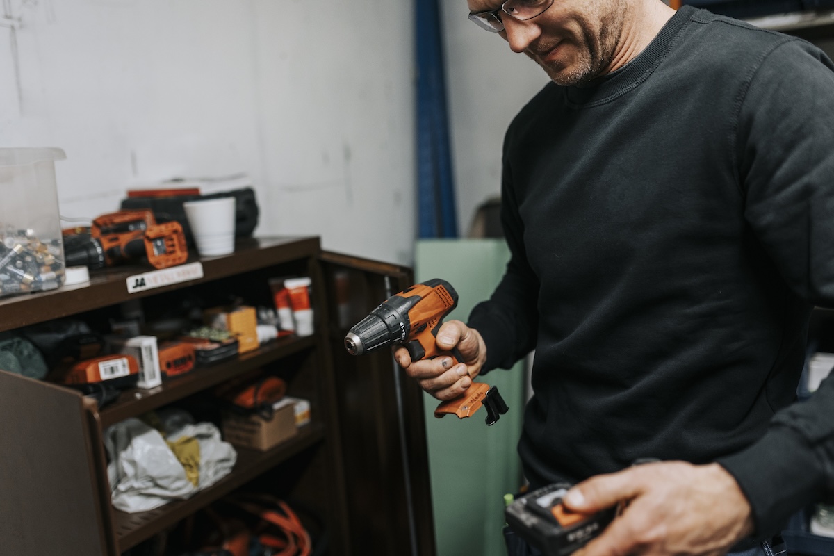 A homeowner using an electric drill with battery inside a climate-controlled garage.