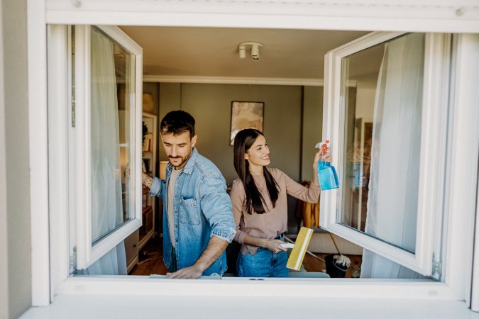 Young couple cleaning windows in their home