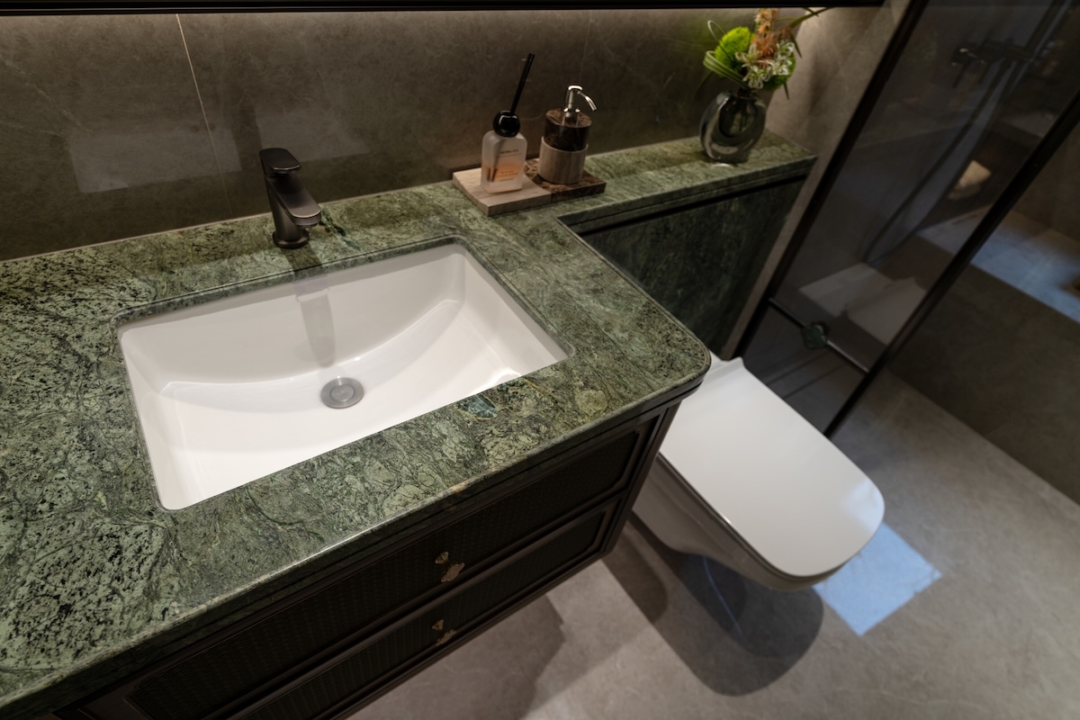 A green granite countertop in a modern home bathroom.