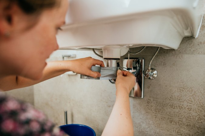 A homeowner trying to fix a plumbing leak with duct tape.