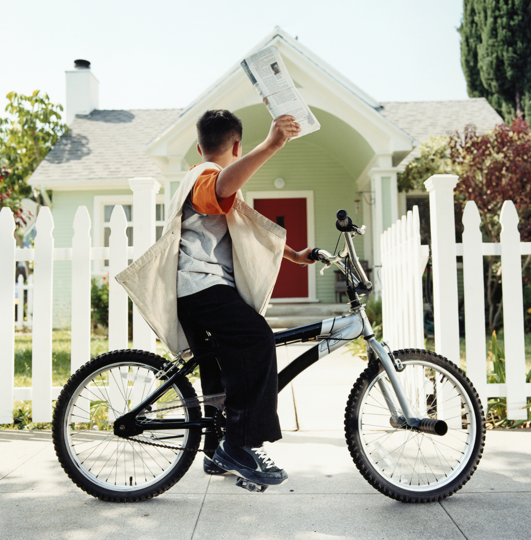 Paperboy delivering a newspaper to a white house with a red door.