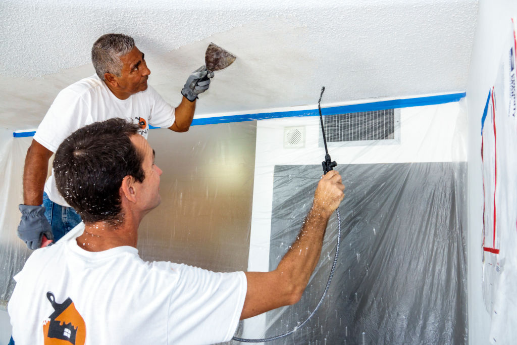 Two men replacing a popcorn ceiling with a flat ceiling