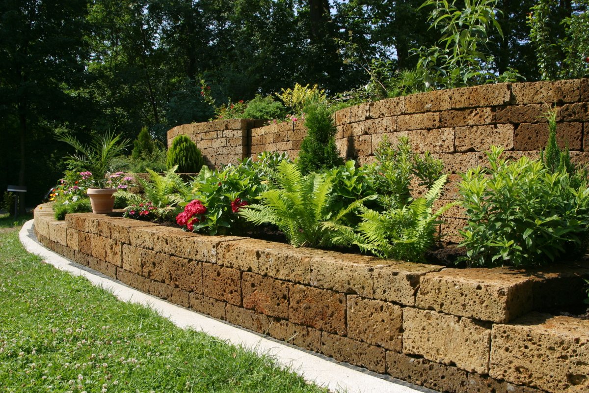 Brown stone retaining wall with plants in backyard