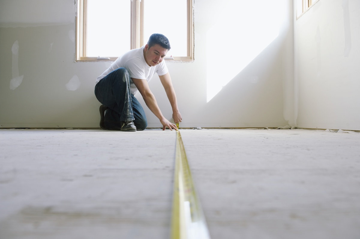 A DIYer measuring the subfloor getting ready to install new flooring.