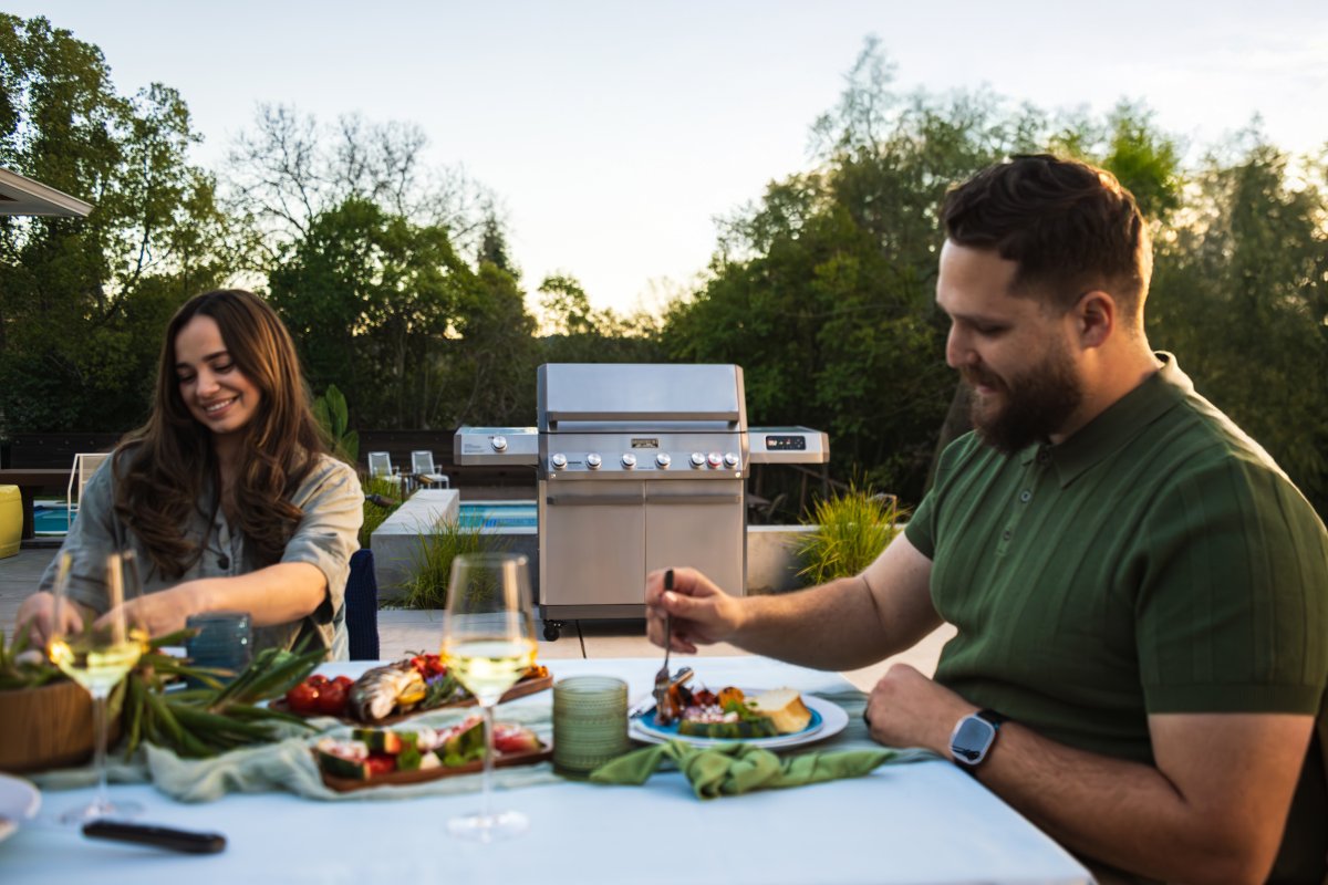 Monument Grills Eminence 605 Grill sitting closed in the background of a backyard BBQ