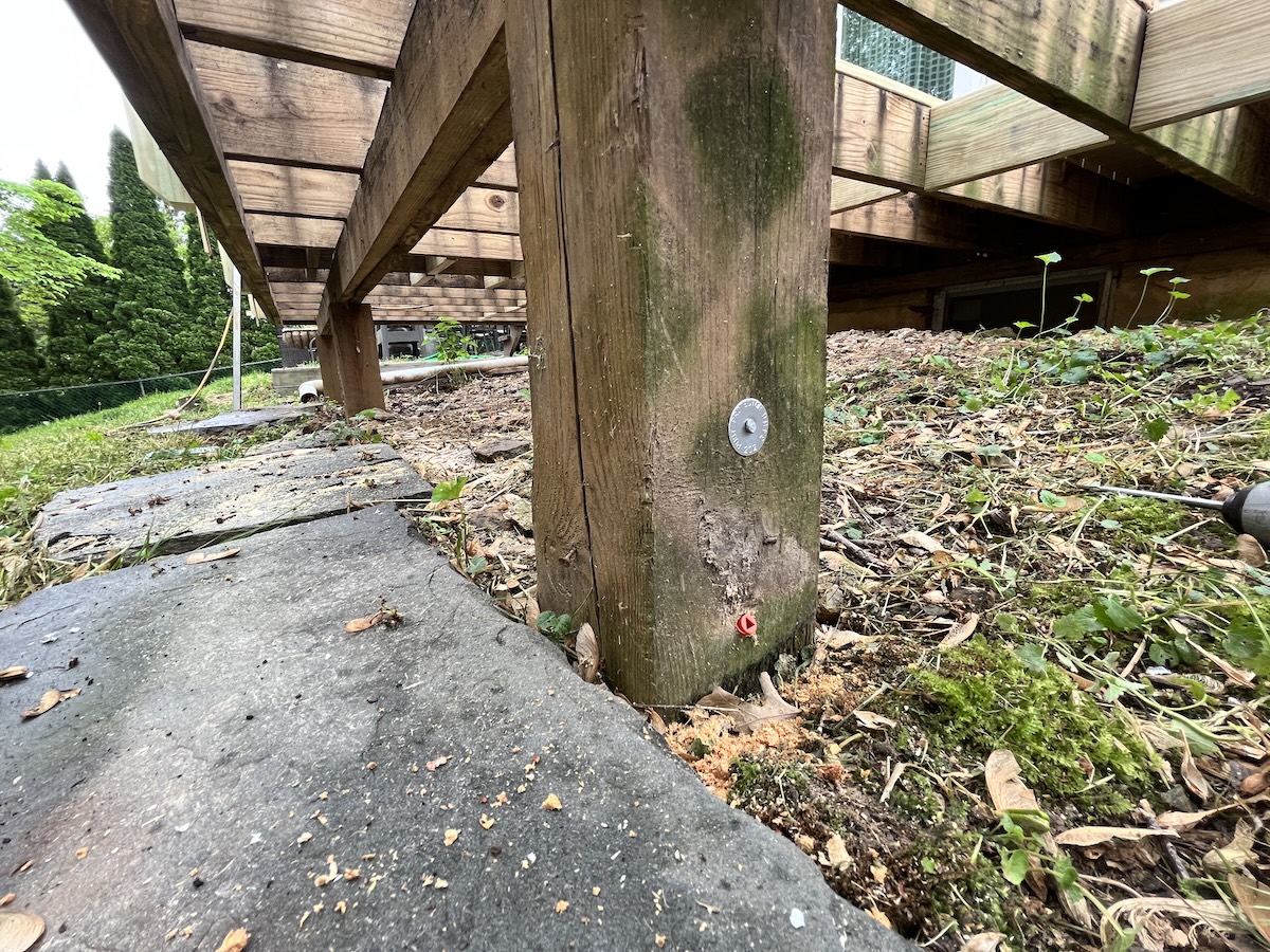 A wood deck post with a preservative inserted into the post.