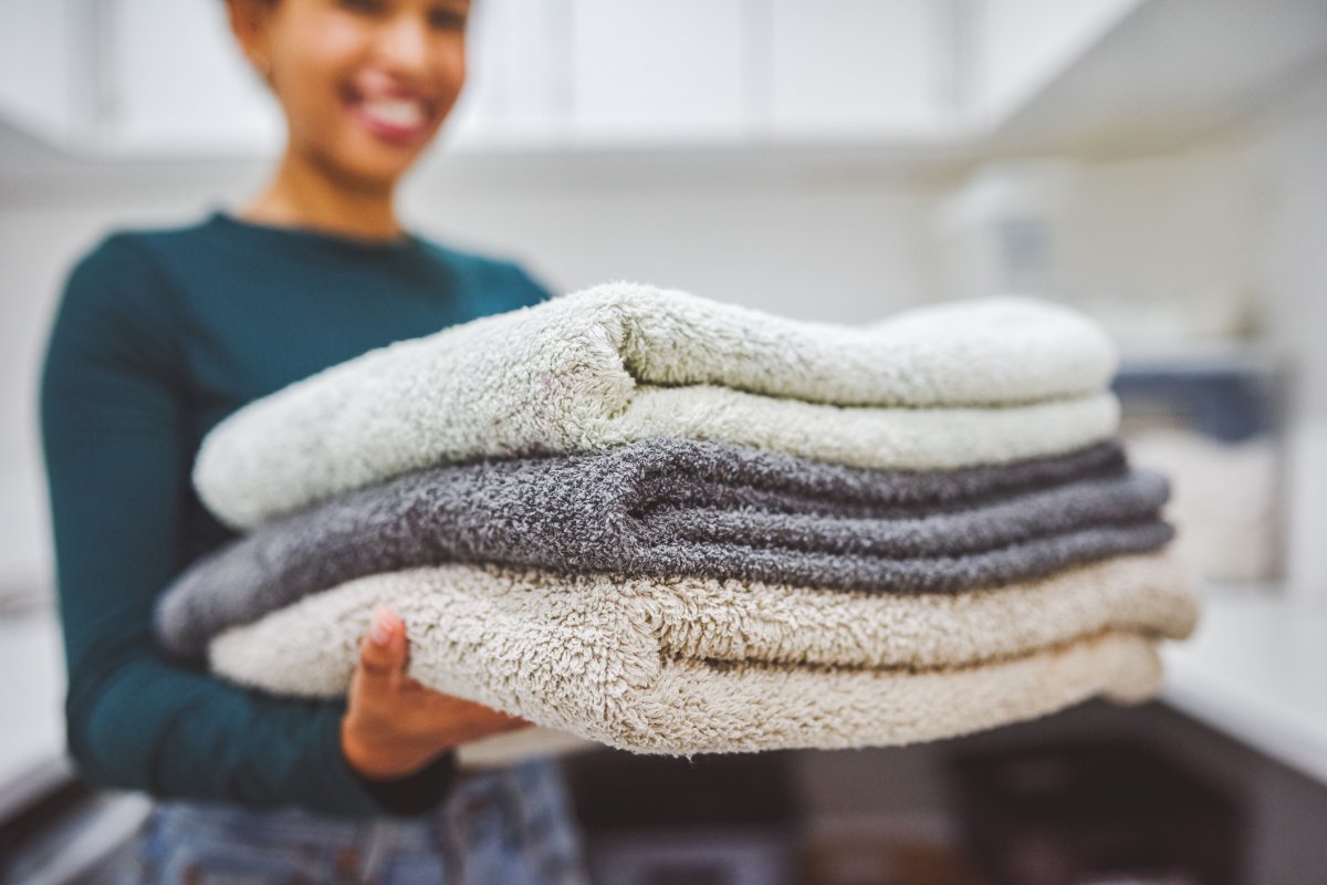 Closeup shot of a woman holding a stack of towels at home