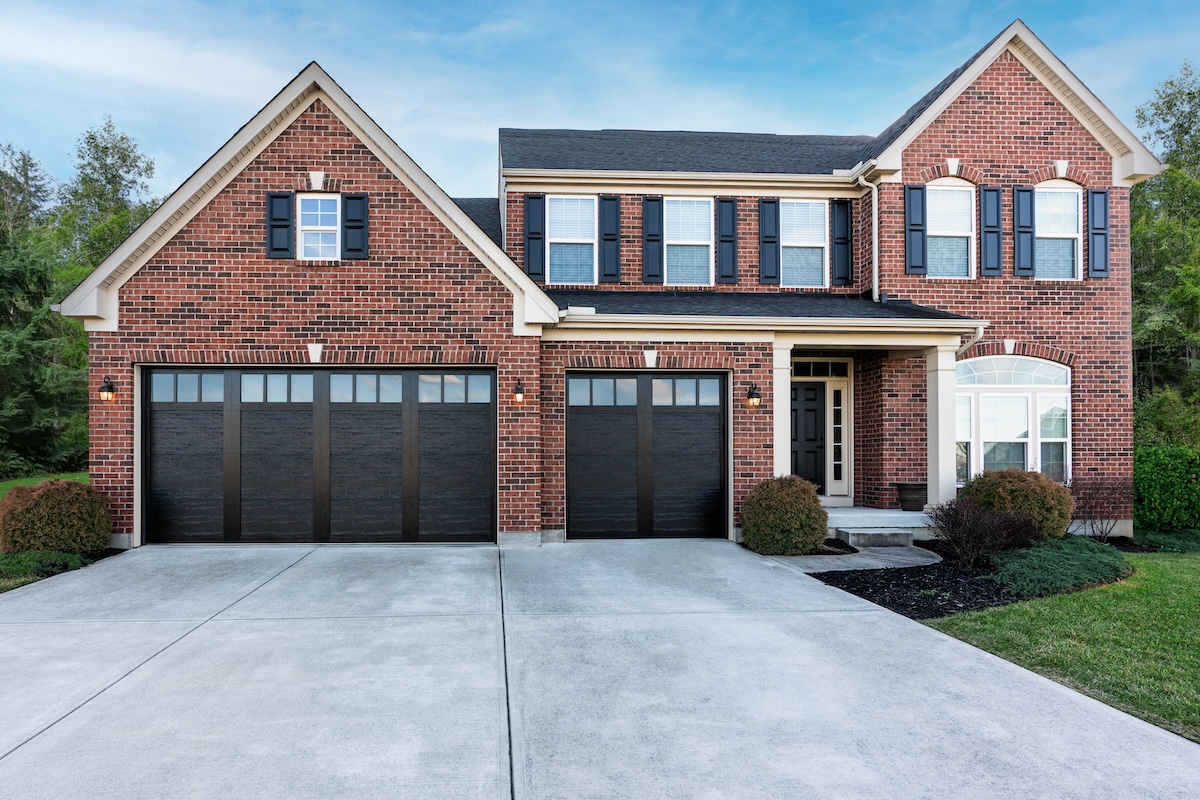 A red brick home with black garage doors.