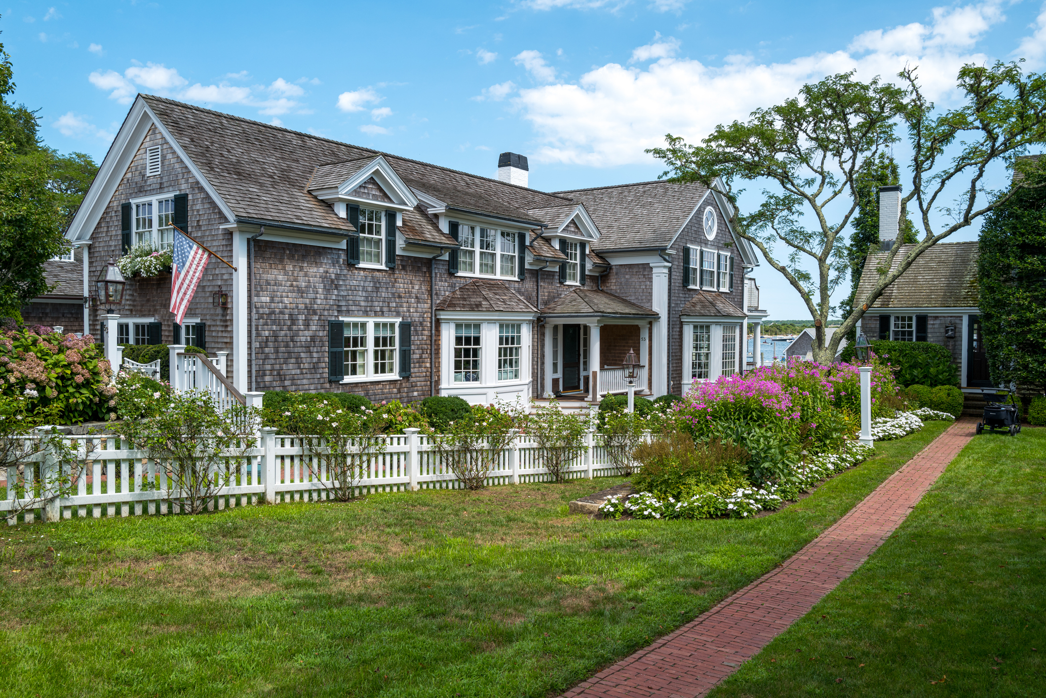 Distinctive grey cape cod home with white picket fence.