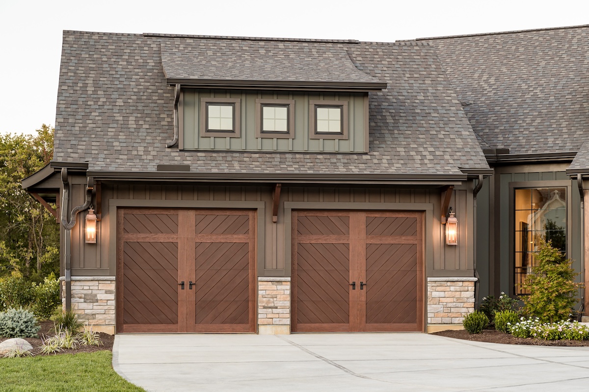 A green and grey home with dark oak is a diagonal pattern on the garage door.