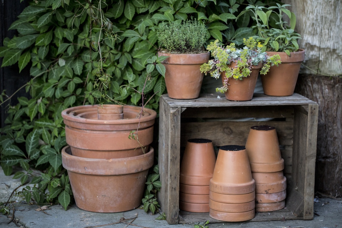 Close up of stacks of terracotta flower pots on a stone floor and wooden box.