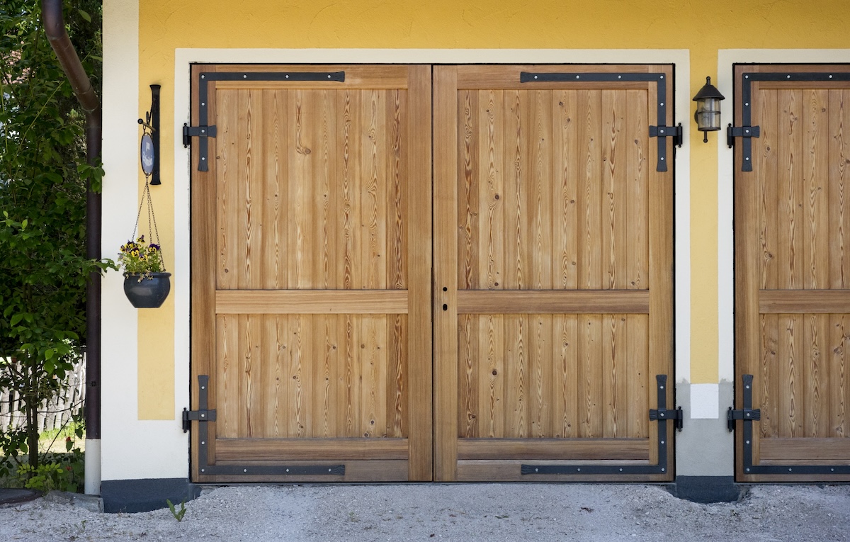 A yellow house with light oak garage doors.